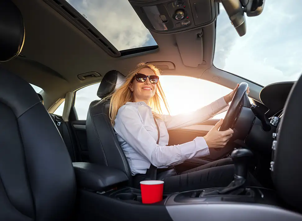 Woman Driving a Car Down a Sunny Road