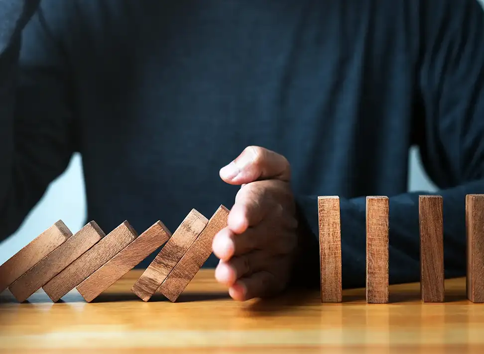 Hand Stopping Falling Dominoes