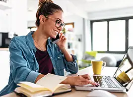 Woman Talking on the Phone While Using a Laptop